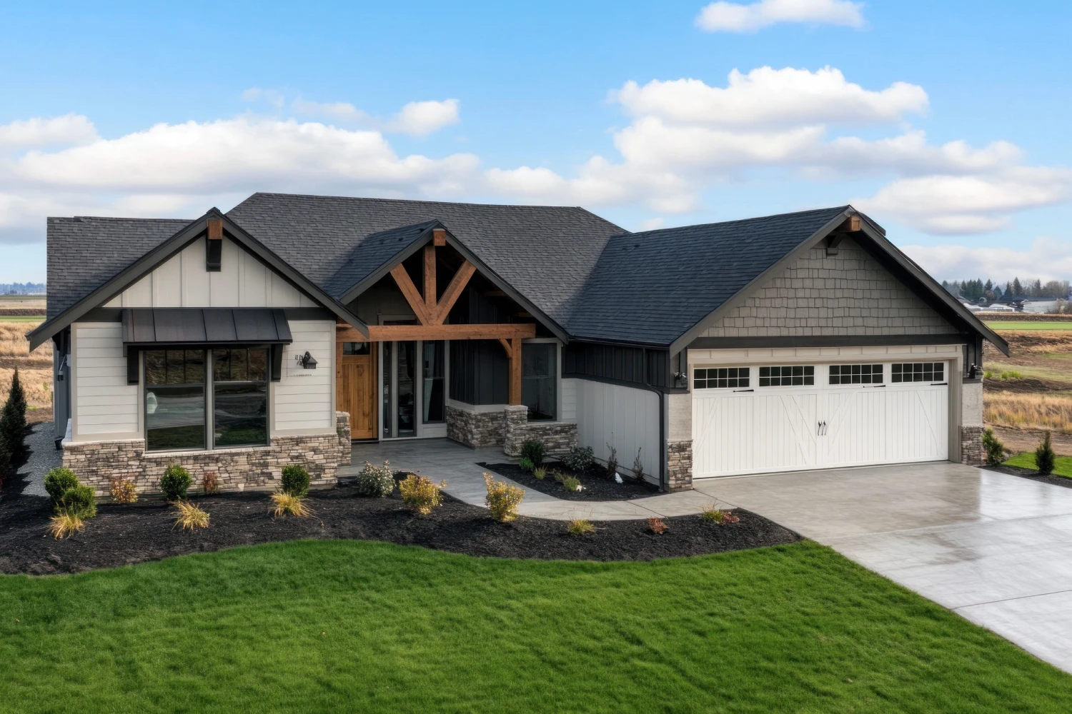 New construction house in Washington state with beautiful landscaping and front yard. The home has a dark brown shingle roof, light gray walls, stone accents on the exterior walls, wooden trim around the windows